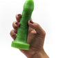 A hand holding up a beginner-friendly silicone dildo, the Uberrime Essential Model A. The toy is a semi-realistic design with an abstractly defined head and subtly curved shaft for g-spot stimulation. It has a flat, flared base. 